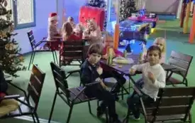 Dzieci siedzą przy stole jedząc II śniadanie