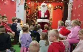 Dzieci siedzą słuchając Świętego Mikołaja