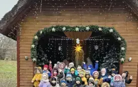 Dzieci stoją oglądając szopkę Bożonarodzeniową