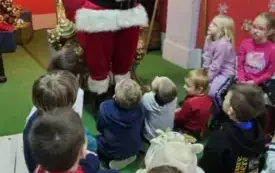 Dzieci siedzą słuchając Świętego Mikołaja