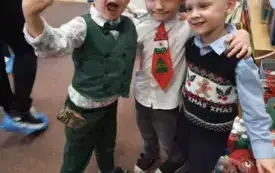 Trzech chłopc&oacute;w obejmuje się. Uśmiechają się na zdjęciu. 