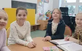 Zdjęcie czterech dziewczynek, absolwentek przedszkola. Siedzą przy stoliku. Uśmiechaja się do zdjęcia.