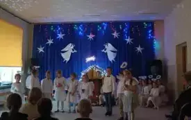 Dzieci ubrane odświętnie. Stoją na środku sali. Z tyłu widać żł&oacute;bek i anioły.