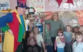 Iluzjonista stoi. Przed nim stoją dzieci. 