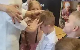 Babcia z zawiązanymi oczami odgaduje przez dotyk  wnuka.