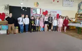 Dzieci stoją na scenie recytują wiersze oraz śpiewają piosenki .