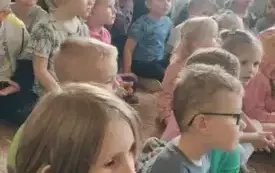 Dzieci siedzą i słuchają muzyki.