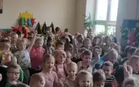 Dzieci tańczą w rytm muzyki. Uśmiechają się.