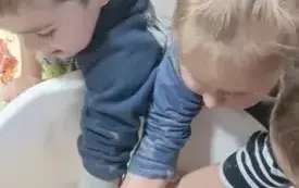 Chłopiec z dziewczynką wkładają ręce do miski. Ściskają mase solną.