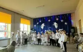 Dzieci stoją na środku sceny. Dziewczynki przebrane są za aniołki.