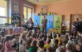 Leśnik stoi przed dziećmi. Dzieci siedzą na dywanie.