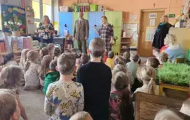 Dzieci siedzą na dywanie i słuchają prelekcji Pana Leśnika