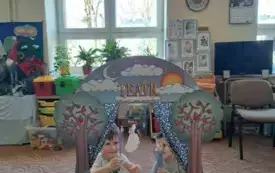 Na dywanie stoi teatrzyk. W teatrzyku są dzieci. Trzymają w rękach wykonane figurki na patyczku.