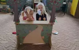 Na dywanie stoi teatrzyk. W teatrzyku są dzieci. Trzymają w rękach wykonane figurki na patyczku.