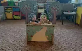 Na dywanie stoi teatrzyk. W teatrzyku są dzieci. Trzymają w rękach wykonane figurki na patyczku.