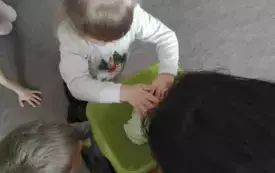 Dziewczynka wciska piankę do zielonej miski. Pani trzyma miskę w ręku.