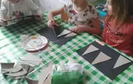 Dzieci siedza przy stoliku. Wykonują prace plastyczną.