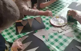 Dzieci siedza przy stoliku. Wykonują prace plastyczną.