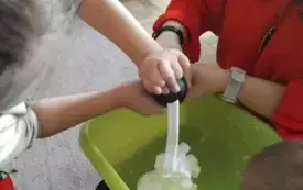 Pani razem z dzieckiem wciskają piankę do zielonej miski. 