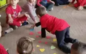 Dzieci siedzą w kole , biurą udział w zabiawie.
