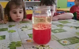 Dzieci obserwują słoik z kolorową wodą.