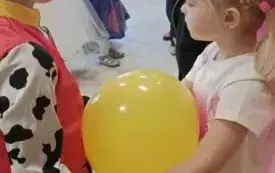 Dziewczynka i chłopiec tańczą z balonem.
