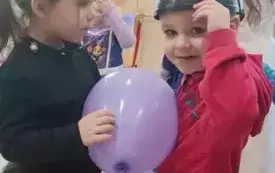 Dziewczynka i chłopiec tańczą z balonem.