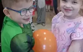 Dziewczynka i chłopiec tańczą z balonem.