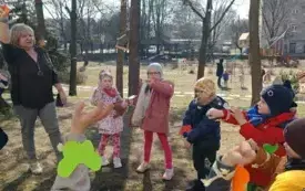 Dzieci stoją w kręgu w ogordzie przedszkolnym.