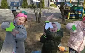 Dzieci pokazują motylki przywieszone na rękach.