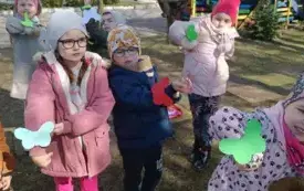Dzieci pokazują motylki przywieszone na rękach.
