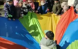 Na środku chusty animacyjnej siedzi chłopiec.