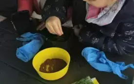 Dzieci posypują ziemię ziarenkami.
