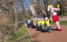 Dzieci trzymają niebieską taśmę ,spacerują .