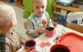 Chłopiec nasypuje ziemię do doniczek