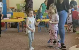 Dzieci stoją w sali przedszkolnej.