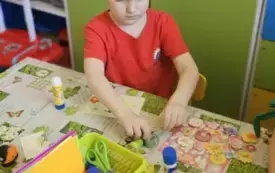Chłopiec wykleja kartkę świąteczną.
