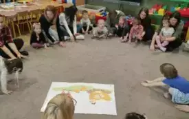 Dzieci z rodzicami siedzą w kole.