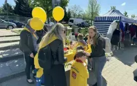 Dzieci stoją z puszką ,uśmiechają się .