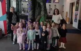 Dzieci stoją przy dużym drzewie w teatrze. Uśmiechają się do zdjęcia.