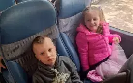 Dzieci siedzą w autokarze. Uśmiechają się do zdjęcia.
