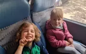 Dzieci siedzą w autokarze. Uśmiechają się do zdjęcia.