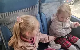 Dzieci siedzą w autokarze. Uśmiechają się do zdjęcia.