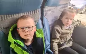 Dzieci siedzą w autokarze. Uśmiechają się do zdjęcia.