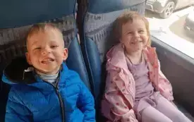 Dzieci siedzą w autokarze. Uśmiechają się do zdjęcia.