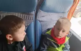 Dzieci siedzą w autokarze. Uśmiechają się do zdjęcia.