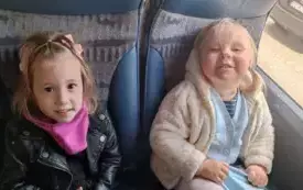 Dzieci siedzą w autokarze. Uśmiechają się do zdjęcia.