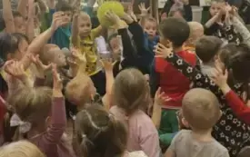 Dzieci podnoszą ręce do g&oacute;ry z piłką