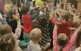 Dzieci podnoszą ręce do g&oacute;ry.