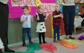 Dzieci stoją a przed nimi leżą kolorowe chusty